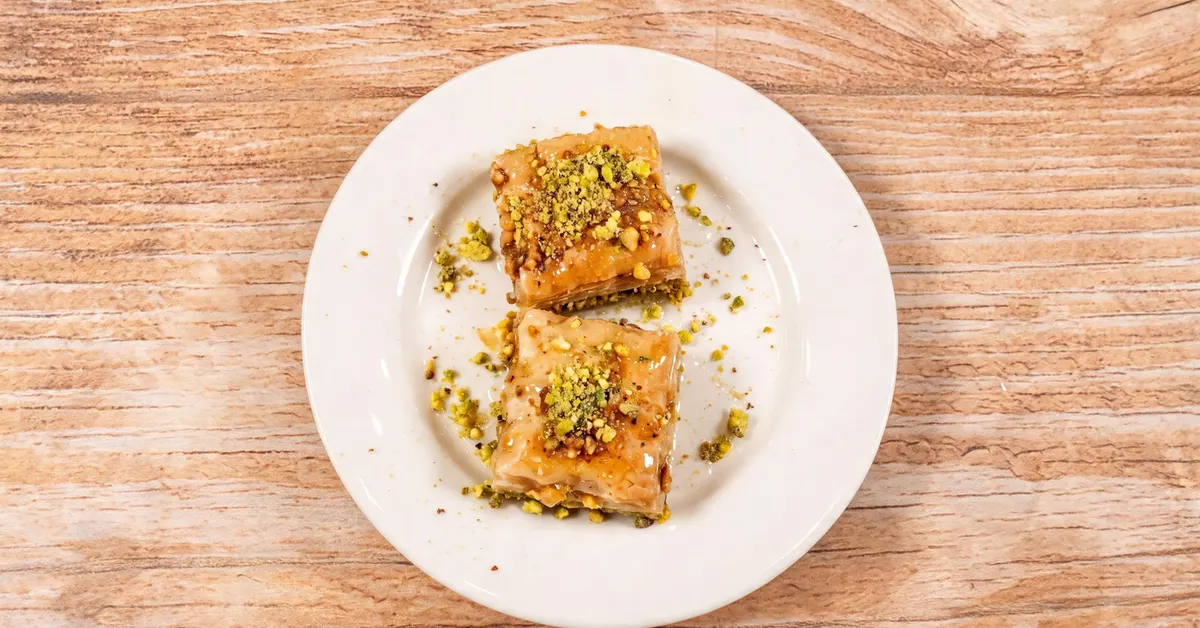 Two squares of pistachio baklava glistening with syrup