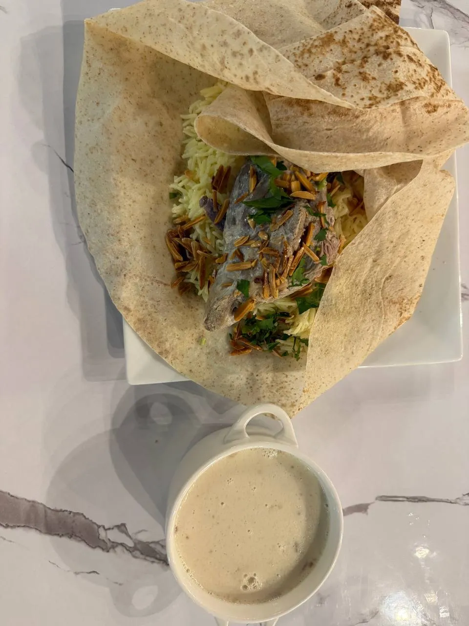 Mansaf: lamb over rice with toasted almonds in shrak bread, with a cup of jameed sauce