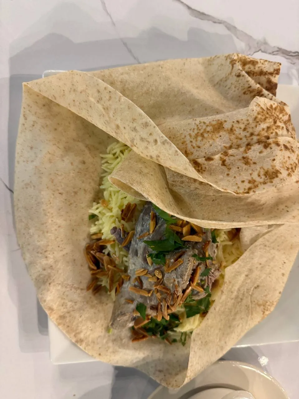 Lamb over rice with toasted almonds and parsley, wrapped in shrak bread