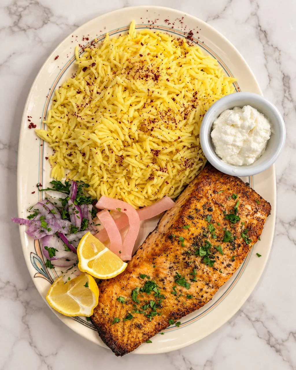 Grilled salmon with seasoned rice, lemon, pickled vegetables, and yogurt sauce